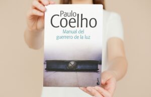 Mujer muestra la portada del libro Manual del Guerrero de la Luz, de Paulo Coelho