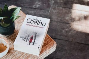 El libro Veronika decide morir, de Paulo Coelho, en una mesa de un jardín, al lado de una planta.
