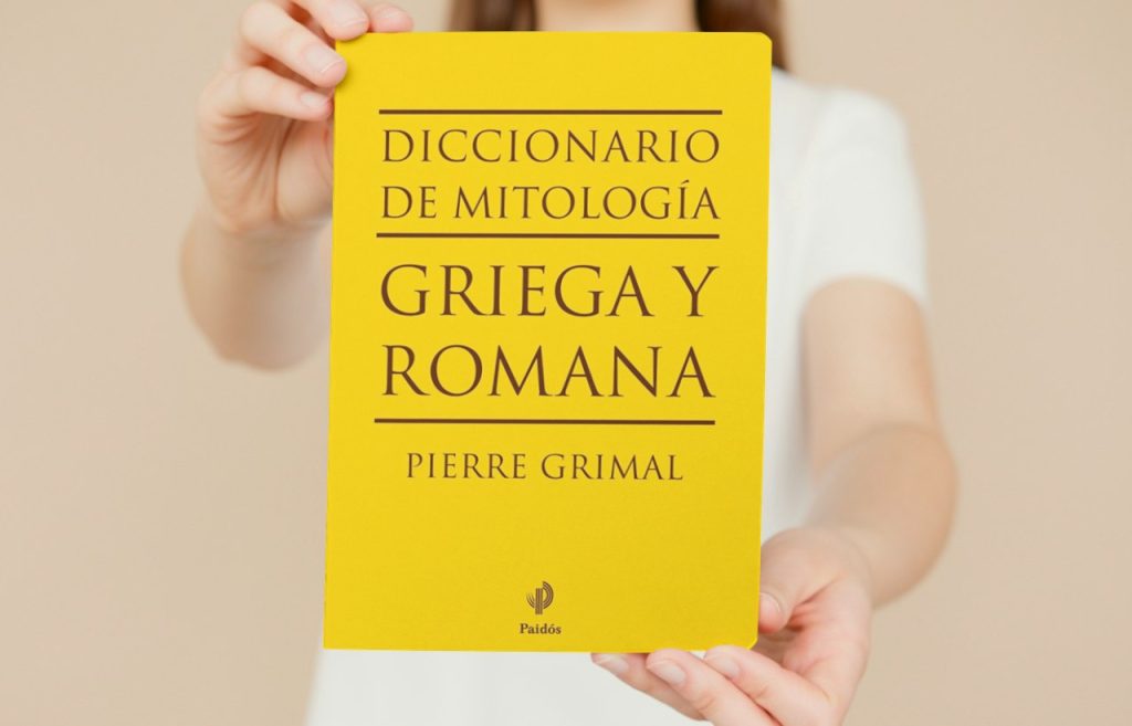 Persona sosteniendo el 'Diccionario de Mitología Griega y Romana' de Pierre Grimal con portada amarilla