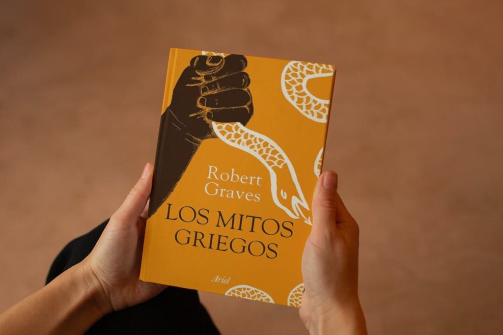 Manos sosteniendo el libro 'Los Mitos Griegos' de Robert Graves con una portada amarilla y diseño de serpiente