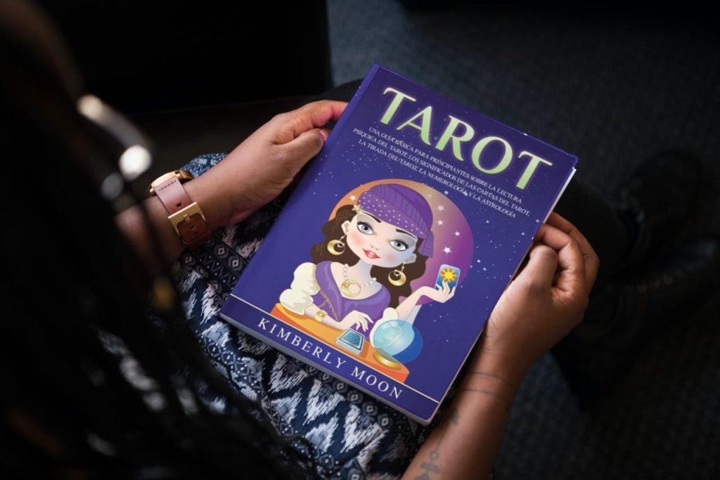 Persona sosteniendo un libro titulado 'TAROT' de Kimberly Moon