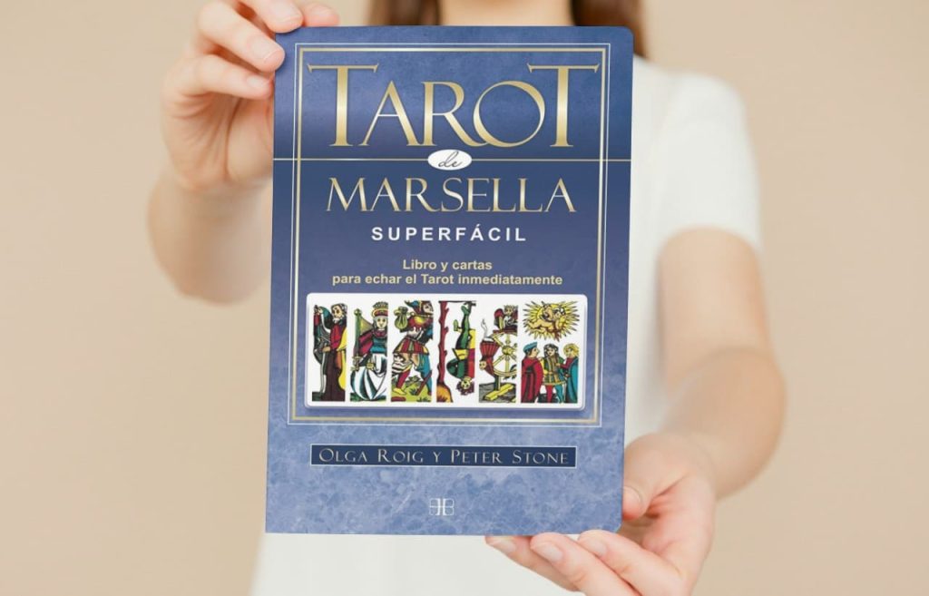 Persona sosteniendo el libro 'Tarot Marsella Superfácil' de Olga Roig y Peter Stone, una guía completa para echar el Tarot