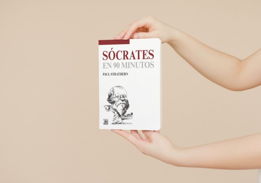 Manos sosteniendo el libro 'Sócrates en 90 minutos' de Paul Strathern, con la portada mostrando una ilustración clásica de Sócrates y el título destacado en la parte superior.