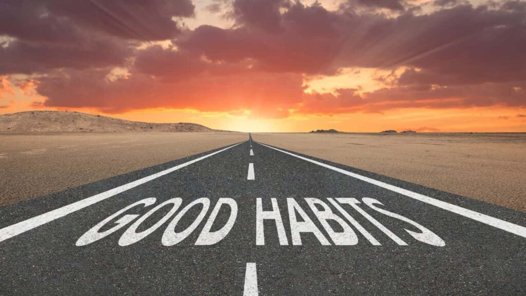 Carretera desértica al amanecer con las palabras 'GOOD HABITS' pintadas en el asfalto, simbolizando el viaje hacia la adopción de hábitos positivos.